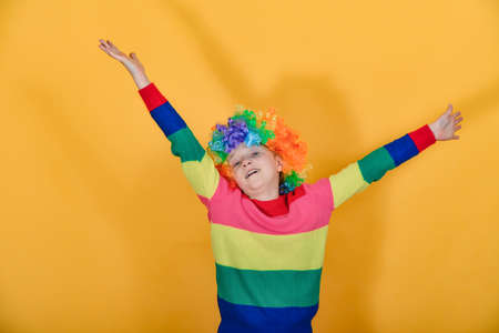 A girl is standing in a multi-colored sweater, waving her arms around the sides in a wig.の写真素材