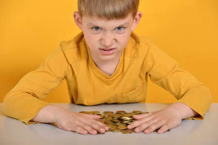 The greedy child took all the coins for himself and does not want to share with anyone.の写真素材