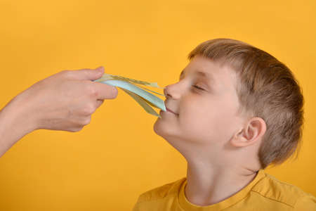 A greedy boy sniffs money with all his greed.