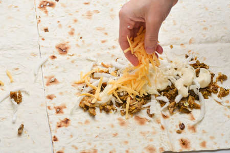 Girl sprinkles shawarma with cheese, hands.の写真素材
