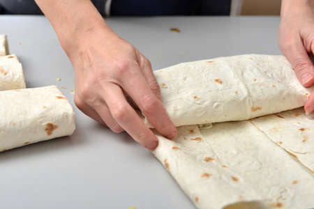 Woman twists ready-made shawarma into pita bread.の写真素材