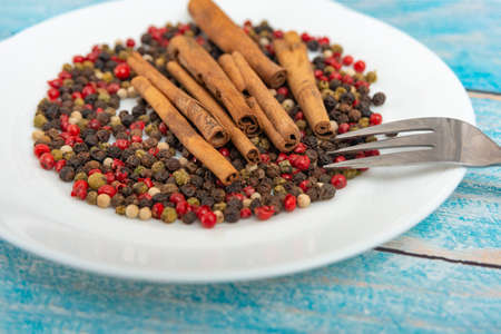 White plate with spices and cinnamon lie on a blue wooden backgroundの写真素材