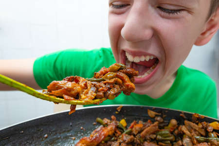 A teenager eagerly eats fatty fried meat, the concept of combining junk foodの写真素材