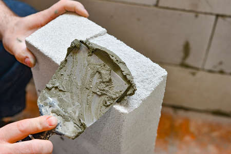 A worker applies adhesive mortar to a wall block in a private house. Foam masonry, repair and...