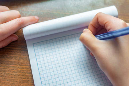 A man holds in his hand a pen for writing on a blank notebook