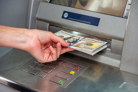 The girl withdraws cash from the ATM.