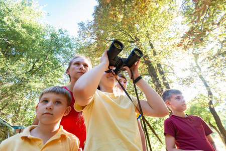 Girl with binoculars. Mom with children looks ahead.の写真素材