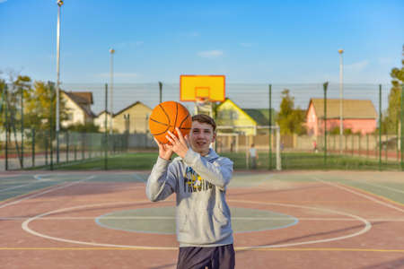 The guy is holding a basketball in his hands and is going to throw it into the hoop on the...