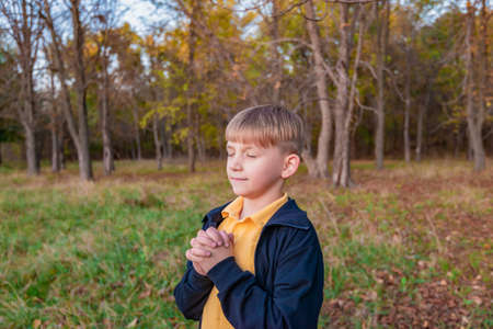 Little boy saying his prayers on a sunny dayの写真素材