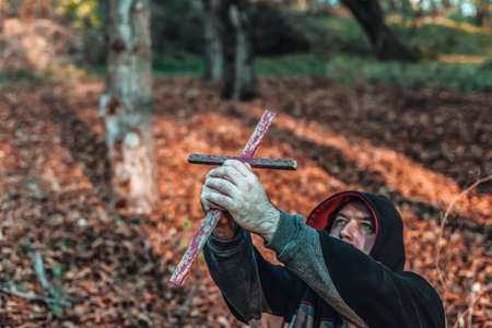 A man kneeling in prayer, raised a Catholic cross to the top, praying and asking for help in the...