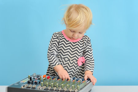 A little girl pushes buttons on a music mixing console.