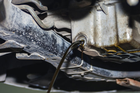 Dirty and used engine oil on a car drains from the engine sump in a car repair shop.の写真素材