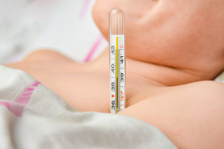 A child with a high temperature lies in bed, at a thermometer of 39 degrees.