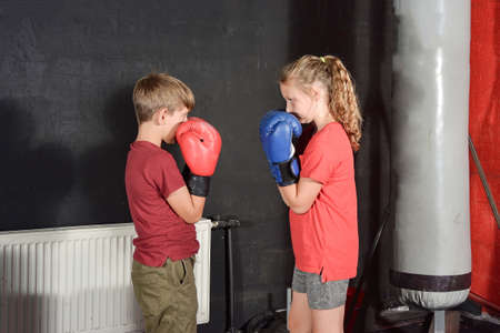 A boy and a girl in boxing gloves greet each other before a fight among the gym.の写真素材