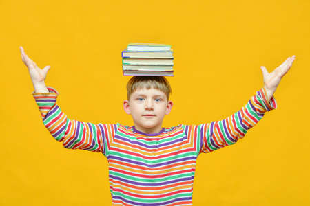 A joyful boy holds a bundle of textbooks on his head and holds his hands at the sidesの写真素材