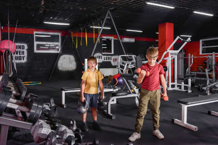 Two boys are engaged in the gym with dumbbells and weights.の写真素材