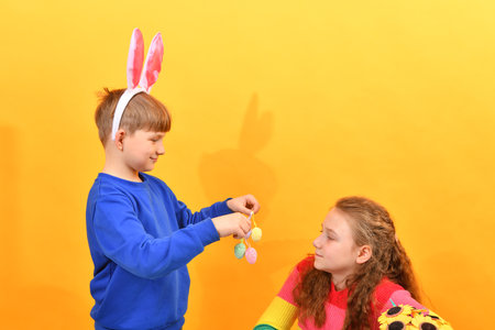 The boy congratulates the girl on Easter and gives her Easter eggs.