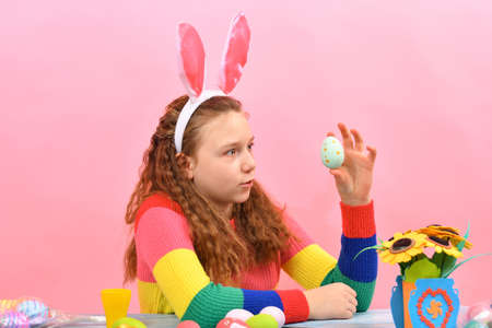 The girl painted an Easter egg and looks at it.