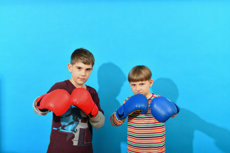 Two young boxers in boxing gloves make an attacker punch on a blue background.の写真素材