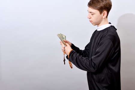 A young Catholic pastor counts dollars after the service. Corruption in Christianity and...