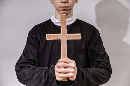 A young Catholic priest holds a cross in front of him. The concept of driving out the devil and evil...