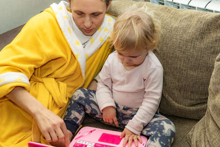 Mom teaches her little daughter on a children's laptop.