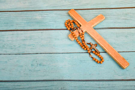 The Catholic cross and rosary lie on a blue textured board. Place for advertisements and text.の写真素材