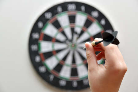 A man aims a dart at a board with numbers.の写真素材
