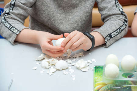 The girl peels boiled eggs from the shell for the Easter holiday.