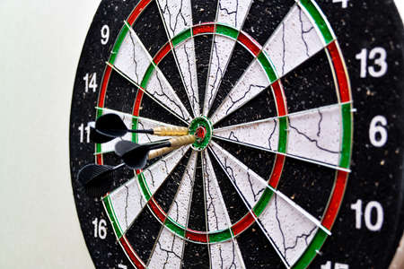 Three darts hit the center of the board while playing darts.