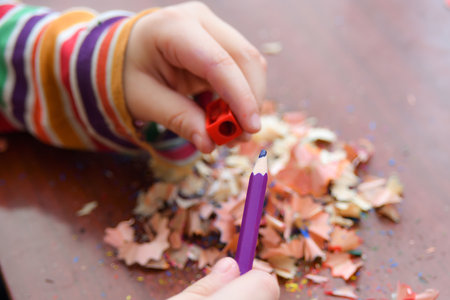 The child sharpens the pencil with a sharpener for further drawing with colored pencils.の写真素材