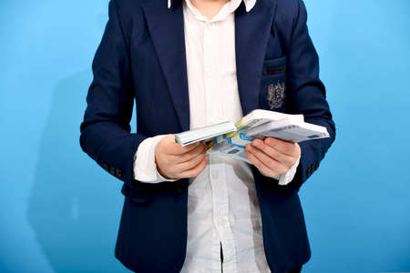 The boy holds in his hand bundles of euro banknotes of 100, 200 and 500 units. Rich child with money on a blue background.の写真素材