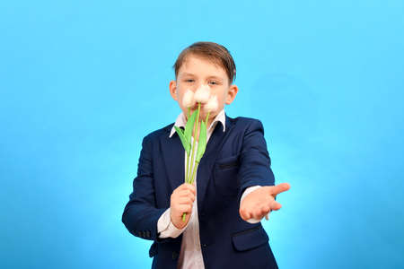 The boy holds tulips in one hand, and stretches out his other hand forward to congratulate on the...