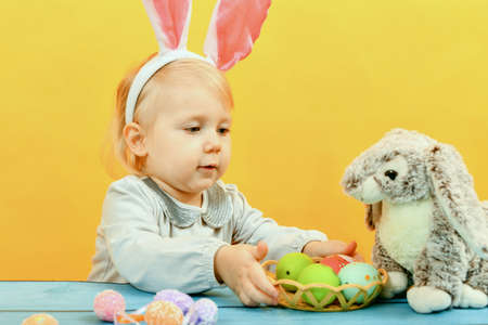 Little girl with pink ears next to the Easter bunny.の写真素材