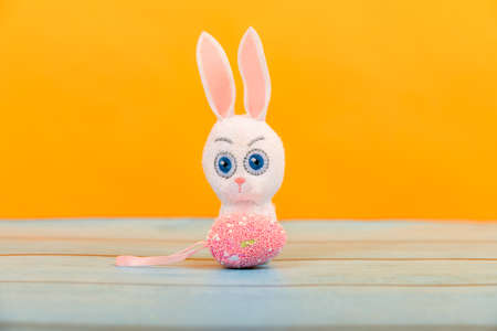 Easter toy bunny with colored festive eggs on a yellow background.の写真素材