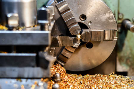 A turner makes a bolt from bronze and brass on a lathe.の写真素材