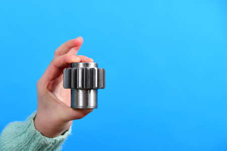 A girl holds a gear wheel in her hand as an advertisement on a blue background.の写真素材