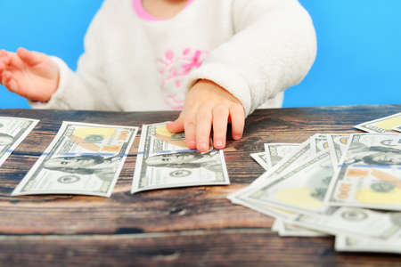 A small child is sorting out dollars on the table and looking at them intently.の写真素材