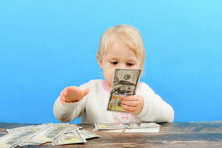 A small child is sorting out dollars on the table and looking at them intently.の写真素材