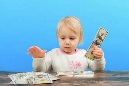 A small child is sorting out dollars on the table and looking at them intently.の写真素材