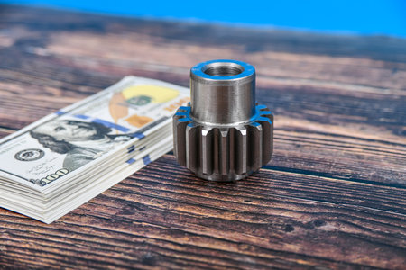 A gear wheel made on a gear cutting machine lies on dollar bills. The concept of advertising and selling industrial engineering servicesの写真素材