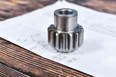 A cogwheel made on a gear cutting machine lies on the technical drawingsの写真素材