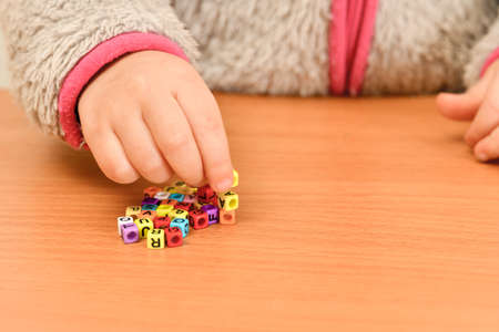 A small child plays with colored letters and tries to put them into words. Preschool education...
