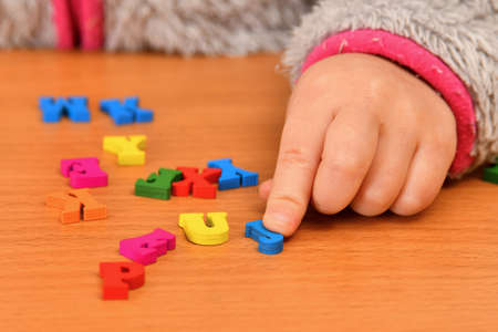 A small child plays with colored letters and tries to put them into words. Preschool education concept.の写真素材