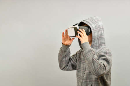 A teenager in a VR helmet is surprised by the immeasurable reality in the virtual world.の写真素材