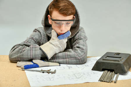 A young welder examines an assembly drawing before work.の写真素材