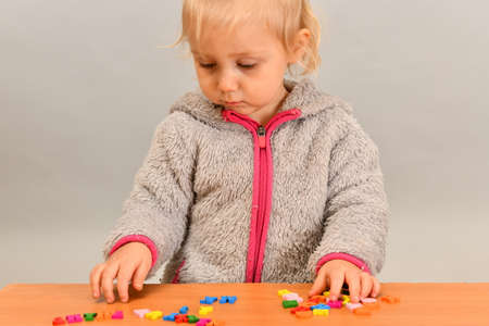 A small child plays with colored letters and tries to put them into words. Preschool education concept.の写真素材