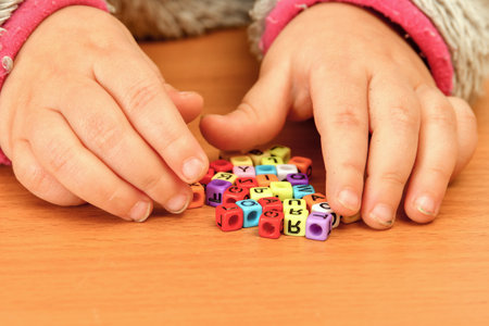A small child plays with colored letters and tries to put them into words. Preschool education concept.の写真素材