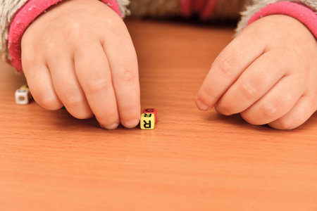 A small child plays with colored letters and tries to put them into words. Preschool education concept.の写真素材
