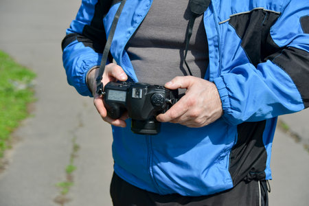 A man looks through the captured images, photographed with a SLR camera in the park.の写真素材